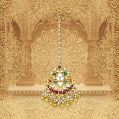 A traditional Indian kundan maang tikka with gold, white, and red stones.