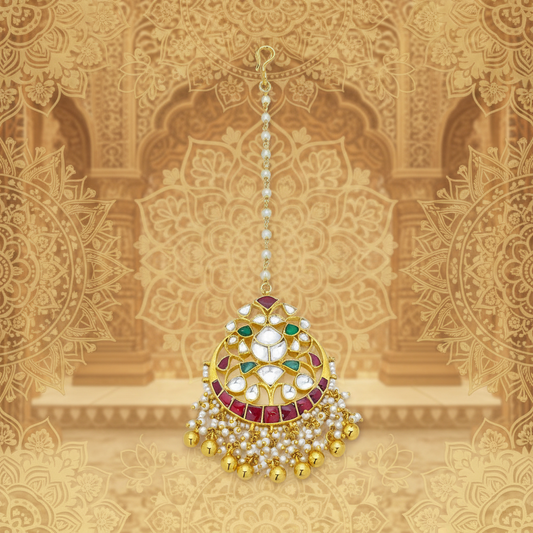 A traditional Indian kundan maang tikka with gold, white, and red stones.